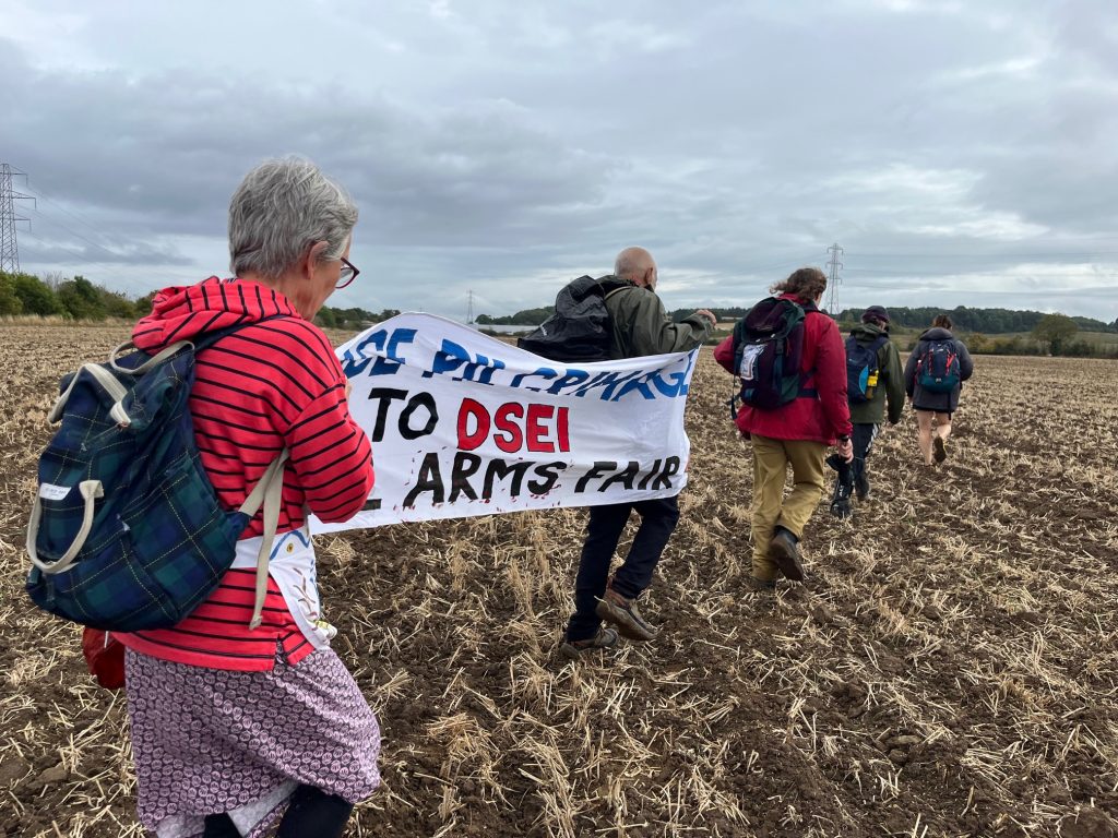 A group of people walking through a field holding a banner