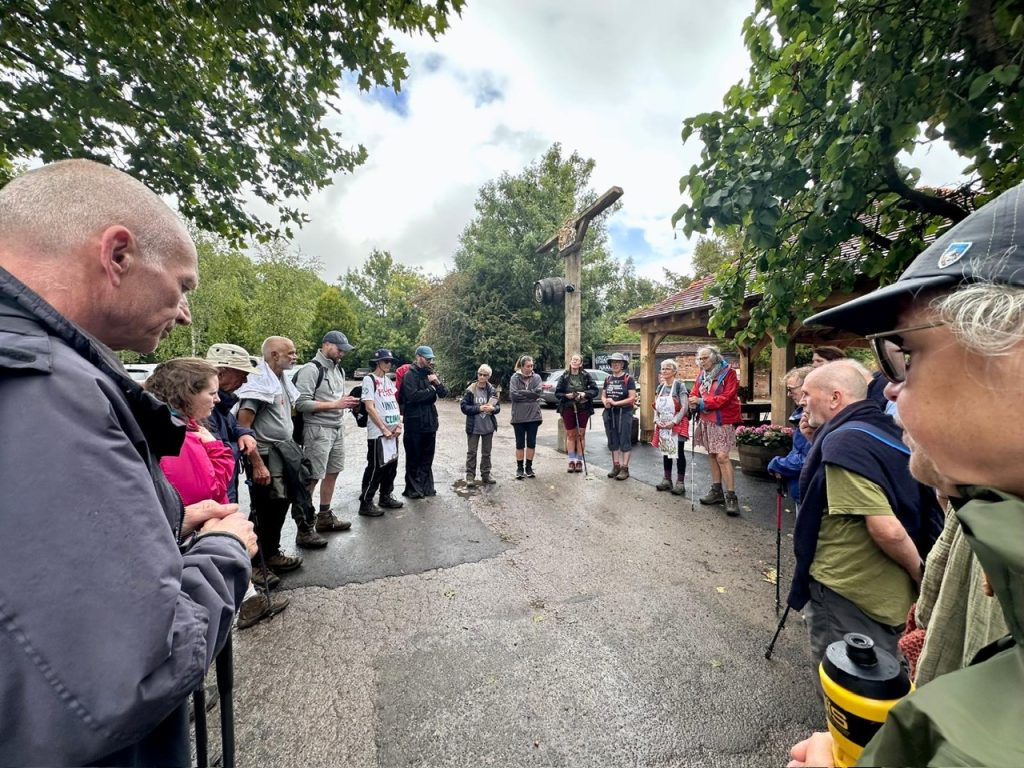 A group of walkers stand gathered in a circle on a road