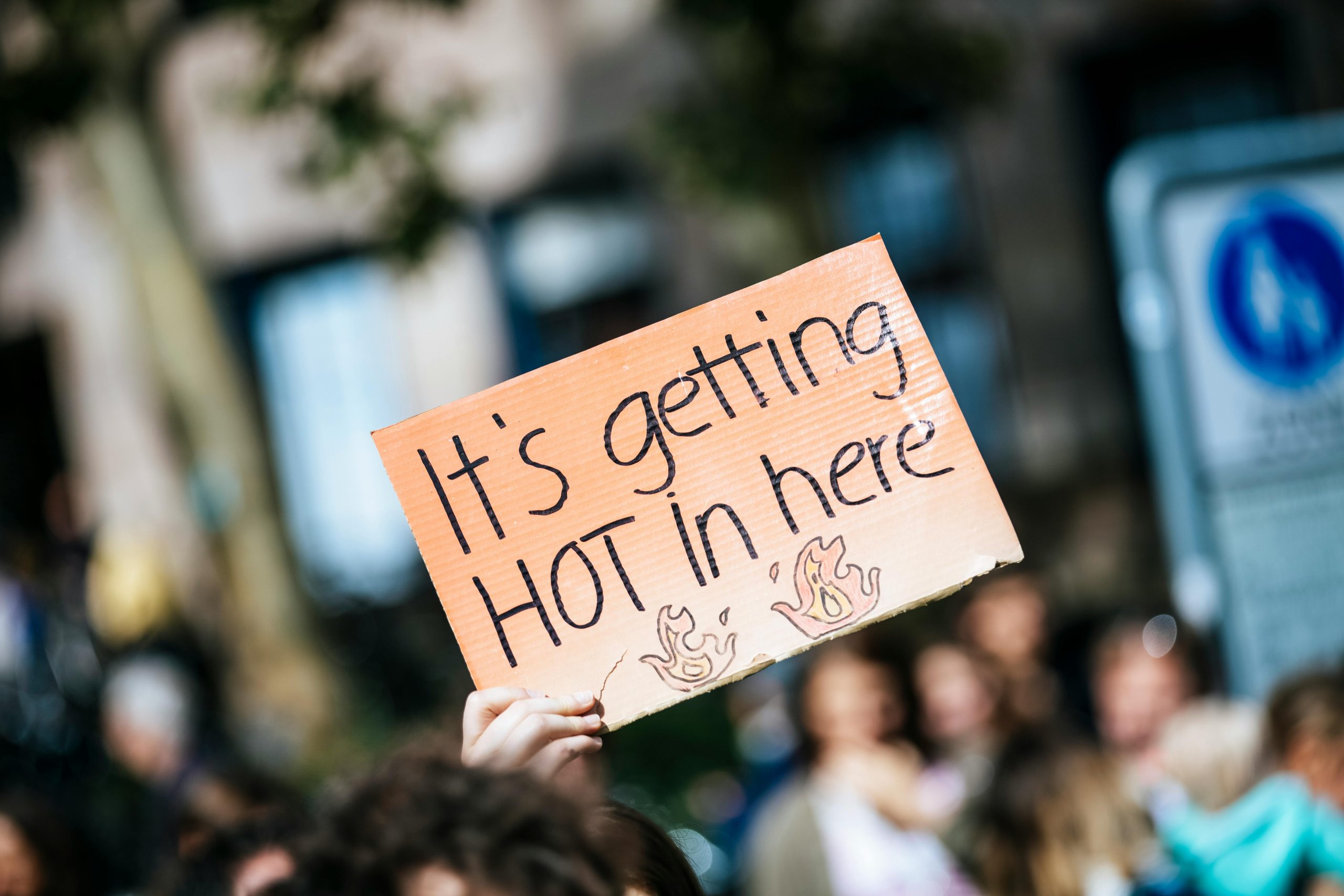 A cardboard protest sign that reads "It's getting hot in here"